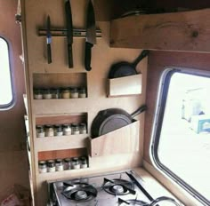 a stove top oven sitting inside of a kitchen next to two open windows with pots and pans hanging on the wall