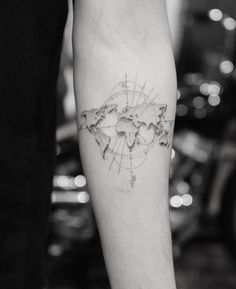 a woman's arm with a tattoo on it that shows the world in her hands