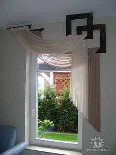 an open window with curtains hanging from it's sides and a blue chair in the foreground