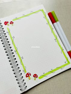 an open notebook with two markers on the cover and a red pen next to it