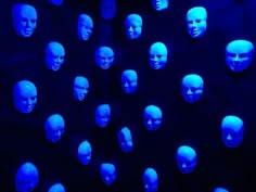 many mannequin heads are glowing in blue light