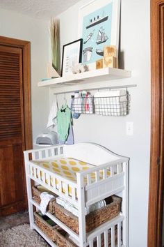 a white crib with baskets on the bottom and shelves above it in a room