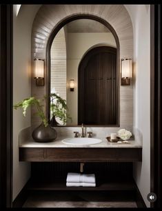 a bathroom with a mirror, sink and vase on the counter in front of it