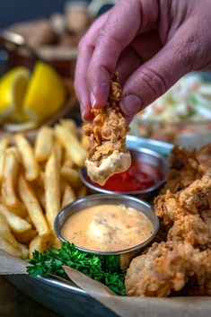 a person is dipping sauce on some fried food