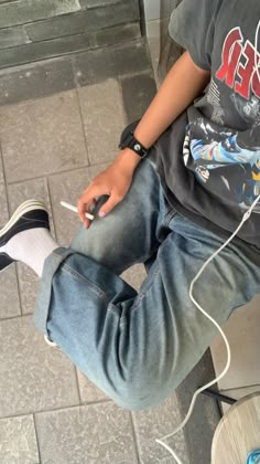 a person sitting on the ground with headphones in their hands