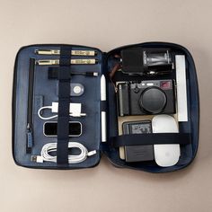 an open blue case with various items in it on a white surface, including a camera and other accessories