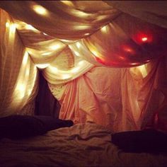 a bed with some lights on the ceiling and curtains hanging down from it's sides