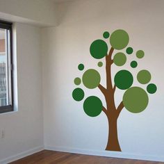 a green room with a tree painted on it's wall and wooden flooring