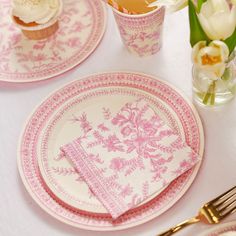 pink and white plates with cupcakes on them are set for a formal dinner