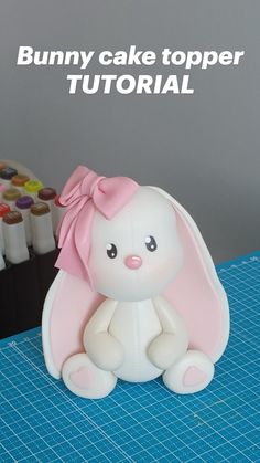 a bunny cake topper is sitting on a table next to some crayons