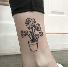 a small tattoo on the ankle of a woman's foot with a potted plant