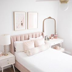 a bedroom with a white bed, pink and gold decor and pictures on the wall