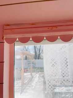 an open window in a pink room with white curtains on the windowsill and outside