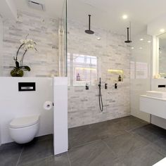 a white bathroom with two sinks, a toilet and a tv mounted on the wall