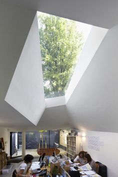 two people are sitting at a table in an open room with skylights above them