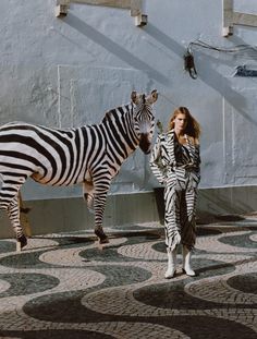 a woman is standing next to a zebra