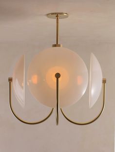 a light fixture with three white glass balls hanging from it's center point and two gold metal arms