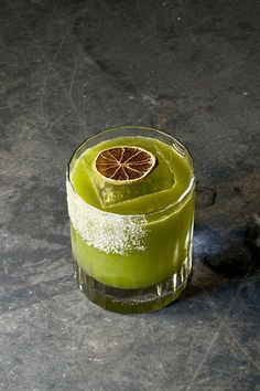 a green drink with an orange slice in it