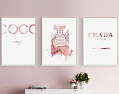 three posters are hanging on the wall above a dresser in a room with pink walls