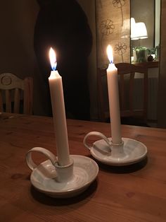 two white candles sitting on top of a wooden table