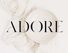 the word adore is surrounded by crumpled white fabric and an empty bowl on top