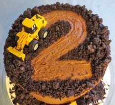 a birthday cake with chocolate frosting and construction vehicles on top, in the shape of s