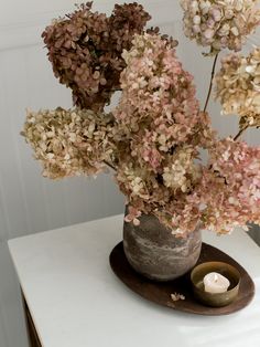 a vase filled with pink and white flowers next to a lit candle on top of a table