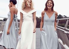 three women in dresses laughing on a bridge