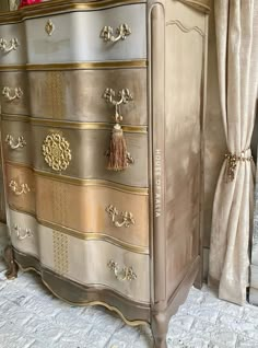 an antique dresser with gold paint and tassels on the drawers is shown in this image