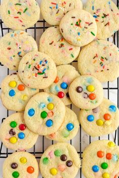 cookies with sprinkles and candies are on a cooling rack, ready to be eaten