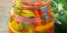 a jar filled with pickles sitting on top of a wooden table next to green peppers