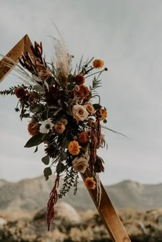 an arrangement of flowers is placed on top of a wooden pole