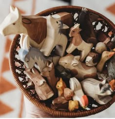 a basket filled with wooden toy animals on top of a table