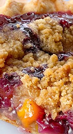 a piece of pie with crumbs and fruit on it sitting on a plate