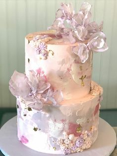 a three tiered cake with pink and purple flowers on it