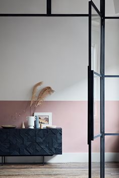 an empty room with pink, white and black stripes painted on the wall next to a sideboard