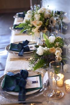 the table is set with place settings, napkins, and flowers on it for an elegant dinner