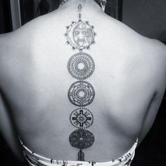 the back of a woman's neck with tattoos on her upper and lower back