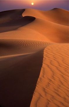 the sun is setting over some sand dunes