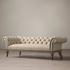 an old style couch sitting on top of a wooden floor next to a white wall