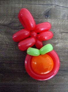 an orange and green plastic object sitting on top of a wooden floor next to a red bowl