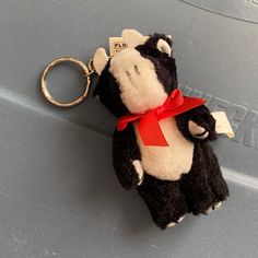 a black and white stuffed animal keychain with a red ribbon around it's neck