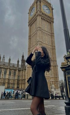 a woman standing in front of the big ben clock tower with her hands to her face