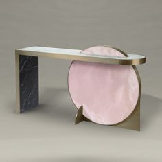 a marble and metal console table with a pink circular object on it's side