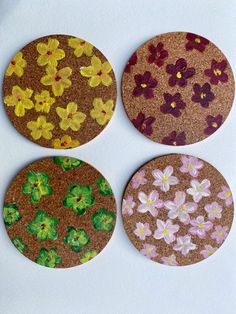 four coasters with flowers painted on them