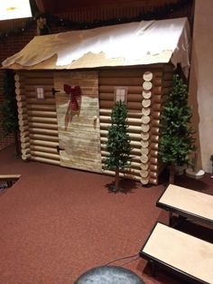 a small log cabin sitting on top of a red carpeted floor next to trees