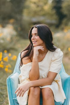 a woman sitting in a blue chair with her hand on her chin