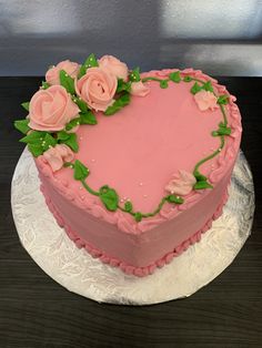 a heart shaped cake with pink frosting and flowers