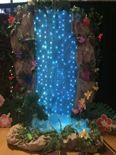 an artificial waterfall with blue lights and flowers