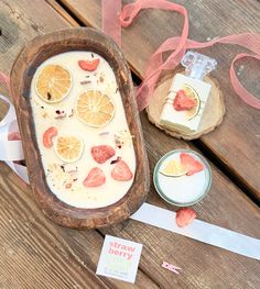 a wooden bowl filled with liquid and sliced oranges on top of a table next to other items